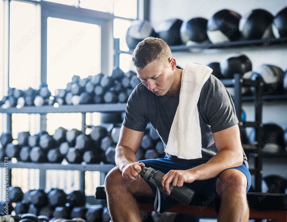 Mid adult man with towel and bottle in gym Mid adult man with towel and bottle in gym