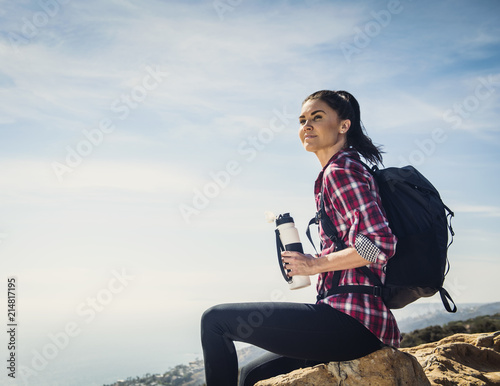 Woman with water bottle sitting on rock