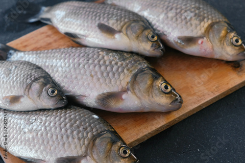 Cooking fish. Fresh small carps on the table on a wooden Board close-up.