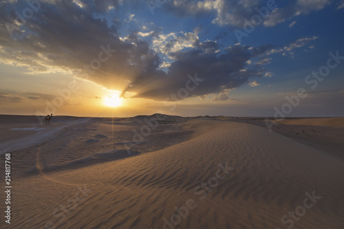 Landscape of sand dune with ripples and clouds at sunset