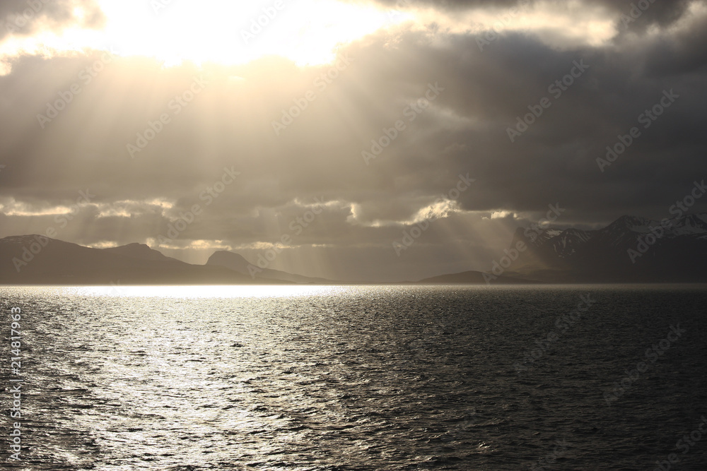 Sun through dark clouds falling on island