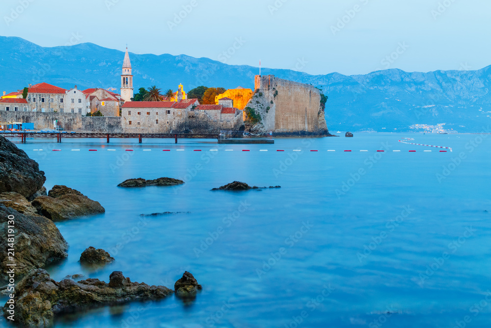 View in the dusk to old city Budva on Adriatic sea coastline at Montenegro, big stones on foreground, blue hour
