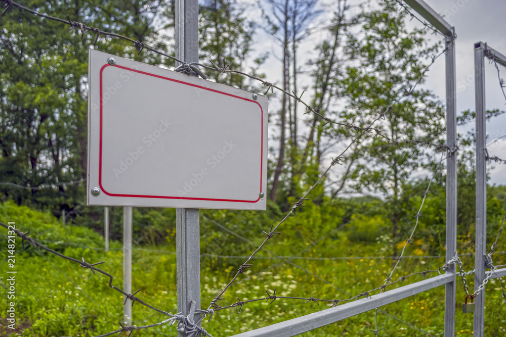 Forbidden area fenced with a barbed wire fence. Gate with padlock closed to the key. Border of States Forbidden area fenced with a barbed wire fence. Gate with padlock closed to the key. Border of States