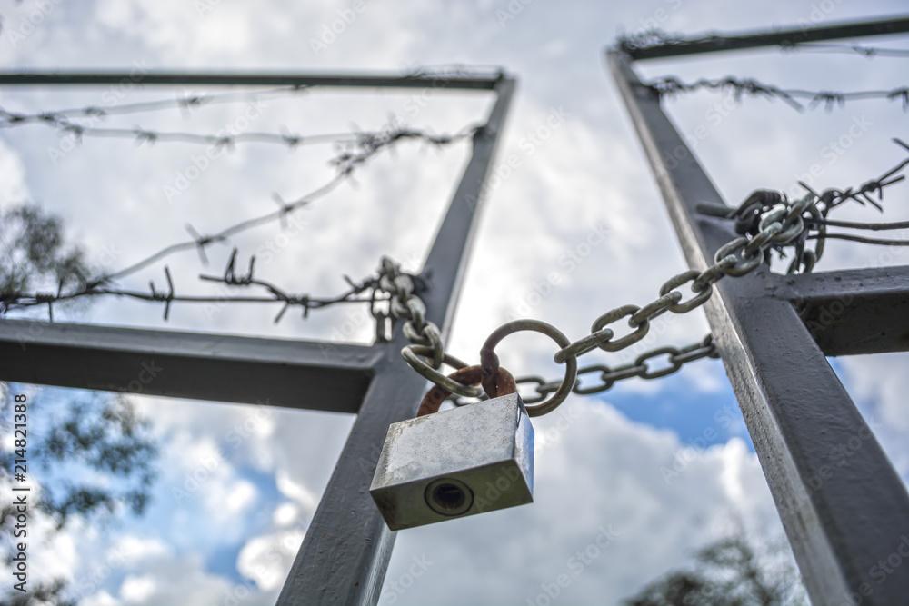 Forbidden area fenced with a barbed wire fence. Gate with padlock closed to the key. Border of States Forbidden area fenced with a barbed wire fence. Gate with padlock closed to the key. Border of States