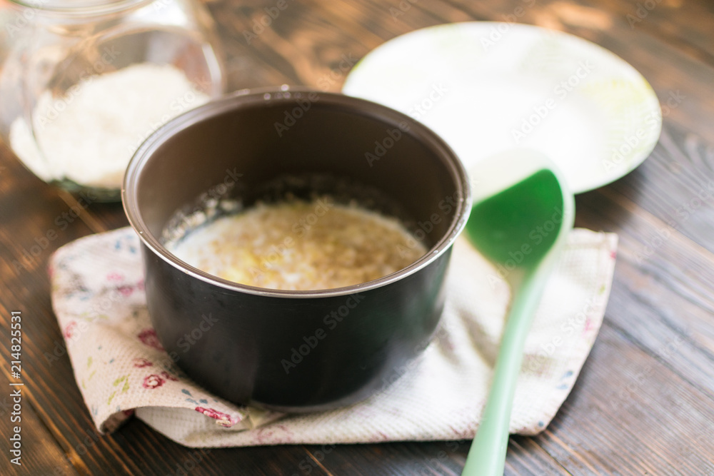 Oatmeal porridge cooked on milk in a saucepan on a dark wooden background. Oatmeal porridge cooked on milk in a saucepan on a dark wooden background.