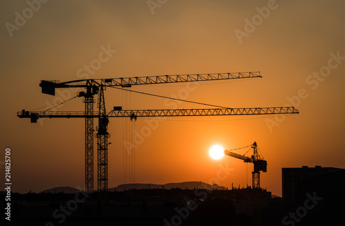 3 Kräne bei Sonnenuntergang vor Dachlandschaft