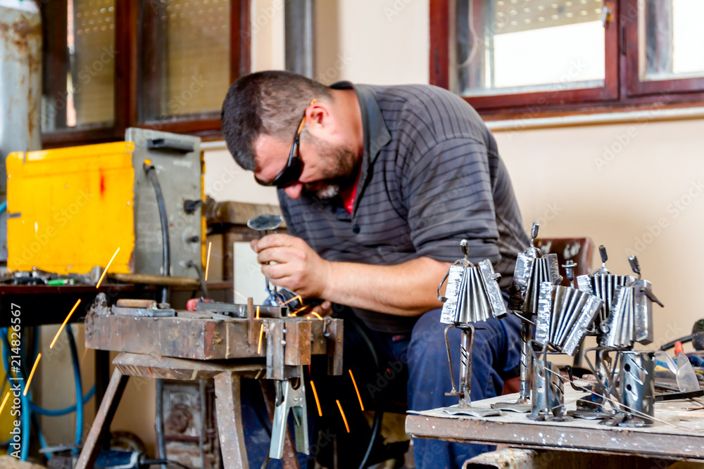 Artist is making figure by welding few metal wires in his workshop, barehanded