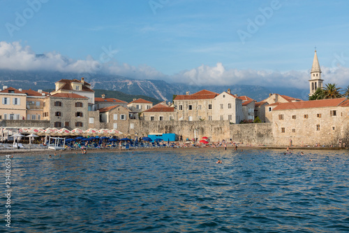 People are relaxing on the beach near the old city in the popular resort of Budva, Montenegro