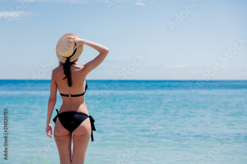 Young caucasian girl in black bikini on a beach in summertime. Odessa, Ukraine