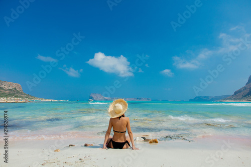 Young redhead girl in black bikini and with hat on Balos beach, west Crete, Greece. Summertime season vacation, July