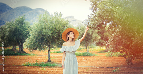 Young redhead girl wearing in dress and hat have a rest in greek olive garden in Heraklion, Crete, Greece