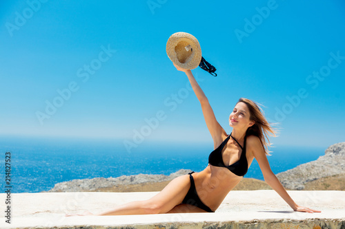 Young girl in bikini on terrace with blue sea and sky on background. Crete, Greece