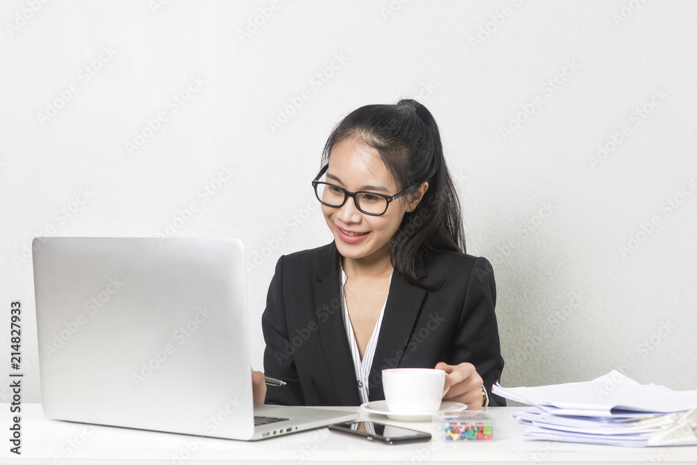 Happy business Asian woman working with laptop at white working table, diligent professional working woman drinking coffee while working on laptop computer. Happy business Asian woman working with laptop at white working table, diligent professional working woman drinking coffee while working on laptop computer.