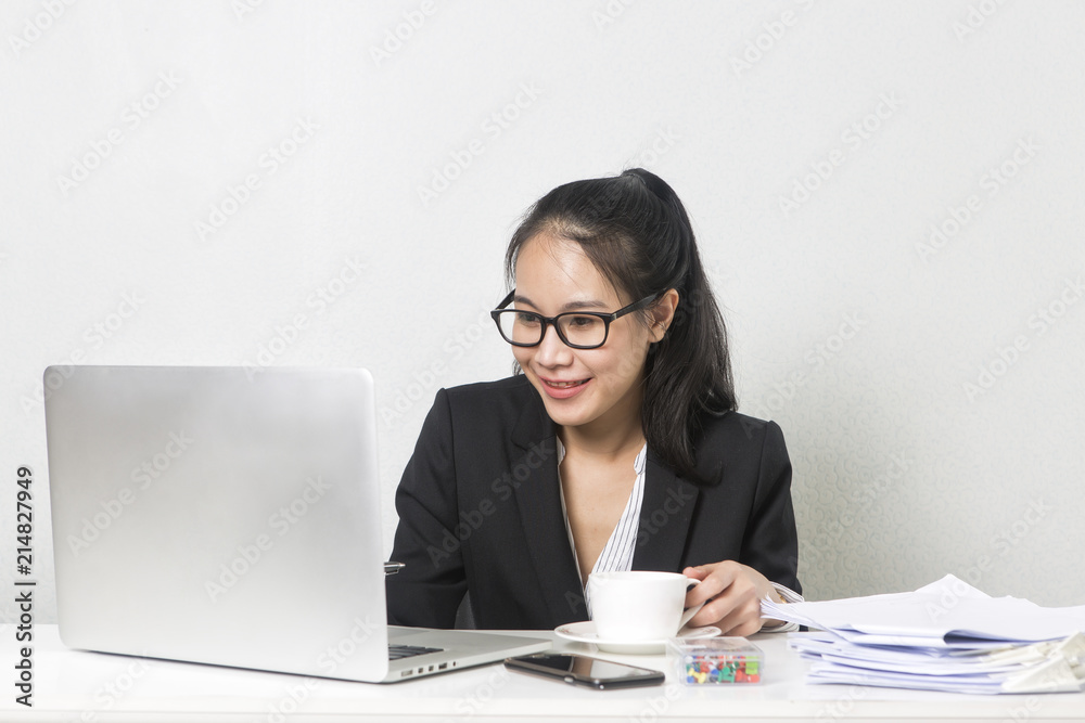 Happy business Asian woman working with laptop at white working table, diligent professional working woman drinking coffee while working on laptop computer. Happy business Asian woman working with laptop at white working table, diligent professional working woman drinking coffee while working on laptop computer.