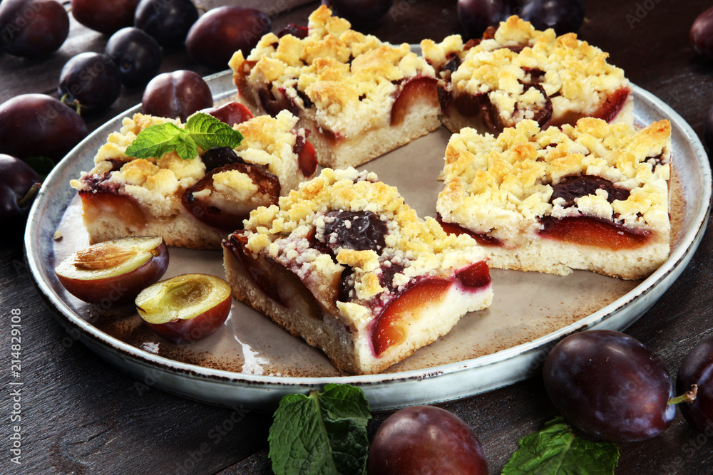 Rustic plum cake on wooden background with plums around. Rustic plum cake on wooden background with plums around.