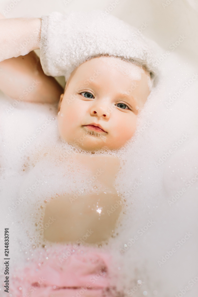 Happy little baby a swimming in the bathroom.Portrait of baby bathing in a bath with foam Happy little baby a swimming in the bathroom.Portrait of baby bathing in a bath with foam