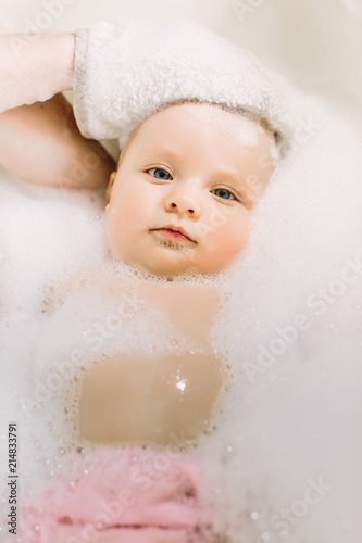 Happy little baby a swimming in the bathroom.Portrait of baby bathing in a bath with foam