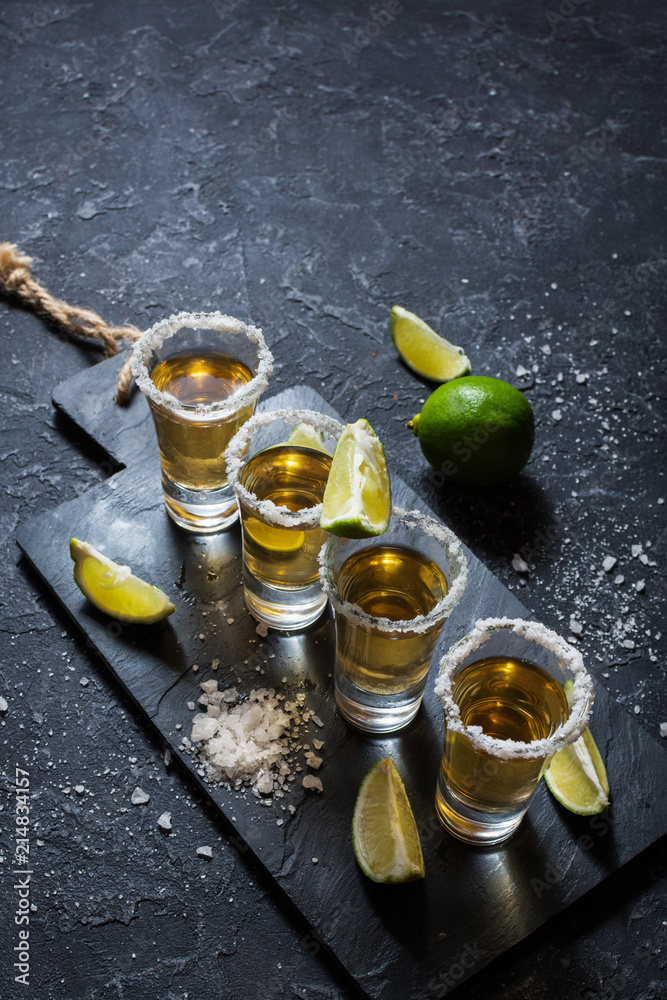 Mexican gold tequila with lime and salt on black stone background. Mexican gold tequila with lime and salt on black stone background.