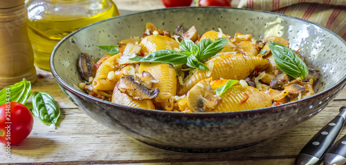Pasta Conchiglioni with mushrooms in a vintage bowl on a dark stone or concrete background. Selective focus