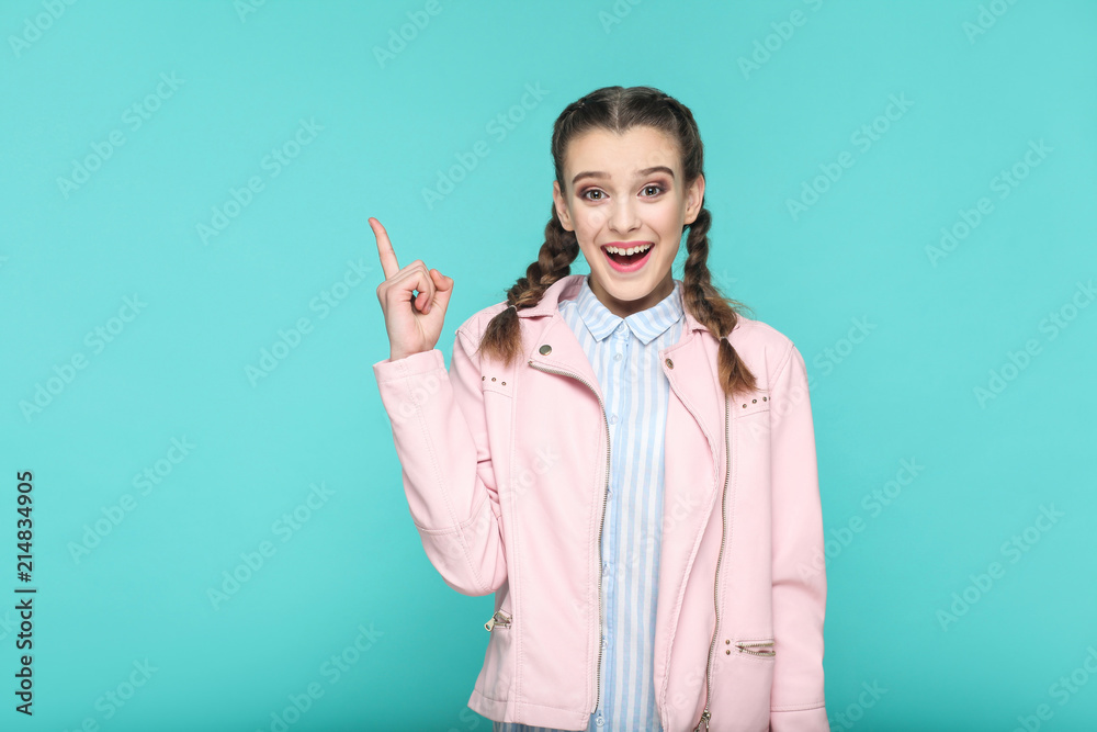 wow I have idea, portrait of beautiful cute girl standing with makeup and brown pigtail hairstyle in striped light blue shirt pink jacket. indoor, studio shot isolated on blue or green background.