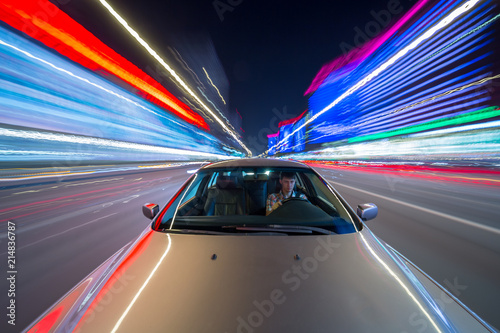 Speed driving on car in night a city with neon glows and motion blured lights.