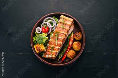 Baked ribs with vegetables. Meat. On a wooden background. Top view. Copy space.