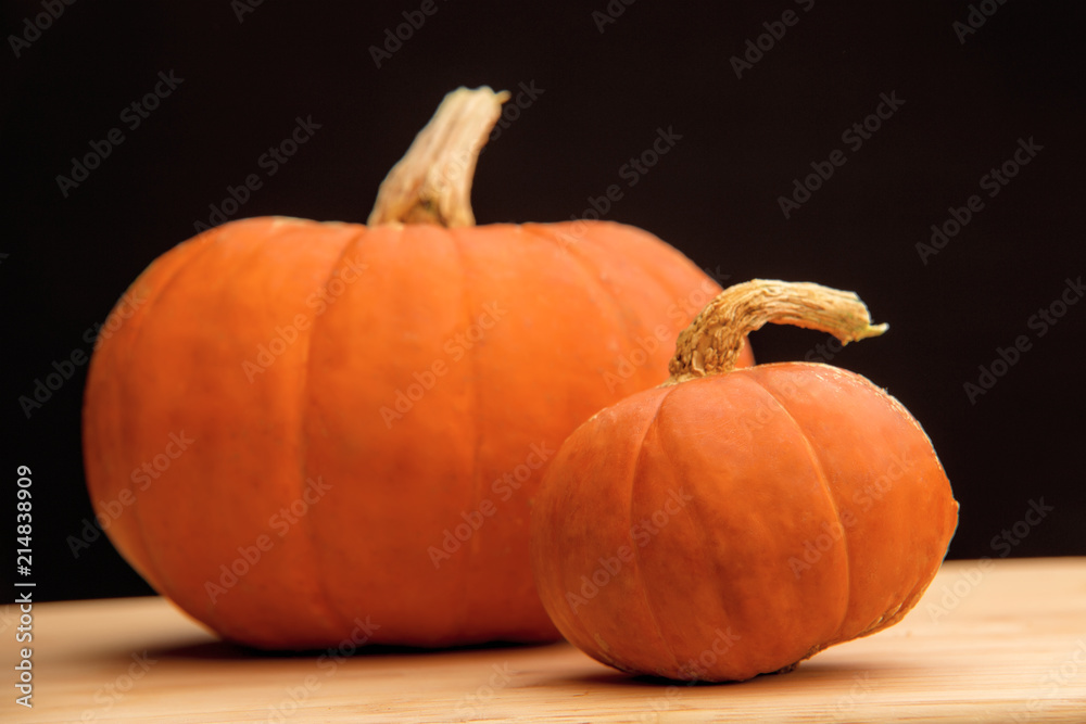 Two pumpkins on a wooden table. Autumn harvest. Black background. Two pumpkins on a wooden table. Autumn harvest. Black background.