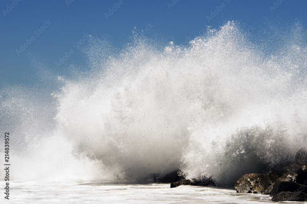 An extreme high wave crashing to rocks in the beach of Venice, California in summertime
