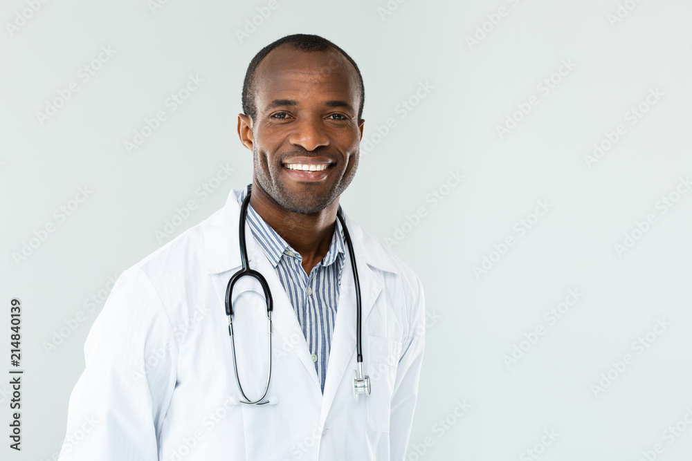 Cheerful doctor standing against background Cheerful doctor standing against background