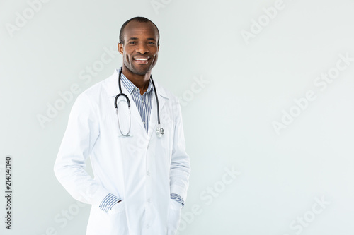Joyful afro american doctor holding his hands in the pockets