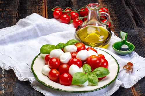 Italian soft cheese, young small balls mozzeralla cheese salad served with fresh basil, tasty ripe cherry tomatoes and Italian olive oil