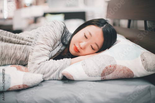 Close portrait of beautiful young asian girl in gray sleeping on a bed with light white pillow with print
