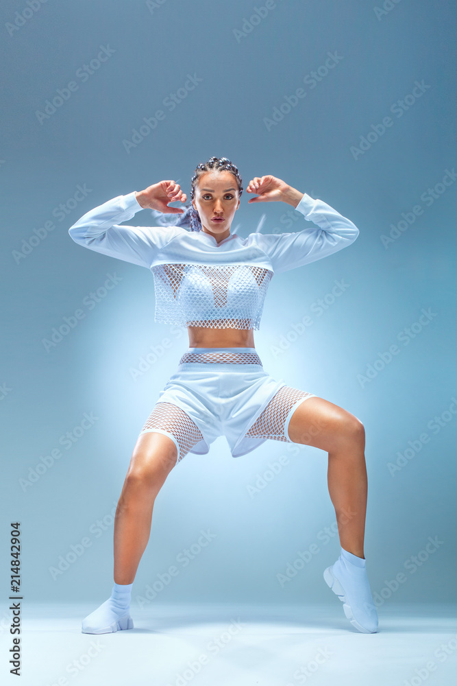 Obraz premium Attractive excited fitness girl dancer in sportwear jumping of joy isolated over gray background