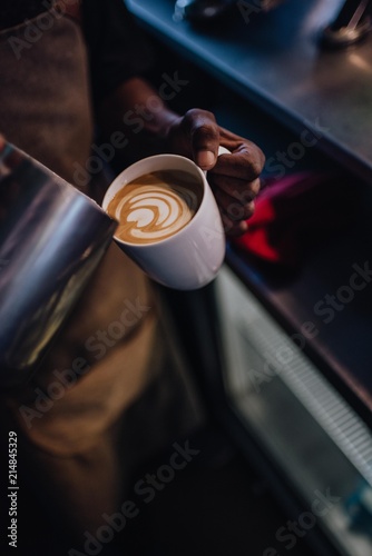 Pouring Latte Art into a cup of coffee by barista at a coffee shop cafe