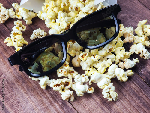 3D glasses on the background of the row of popcorn for movies, space, on wooden background.