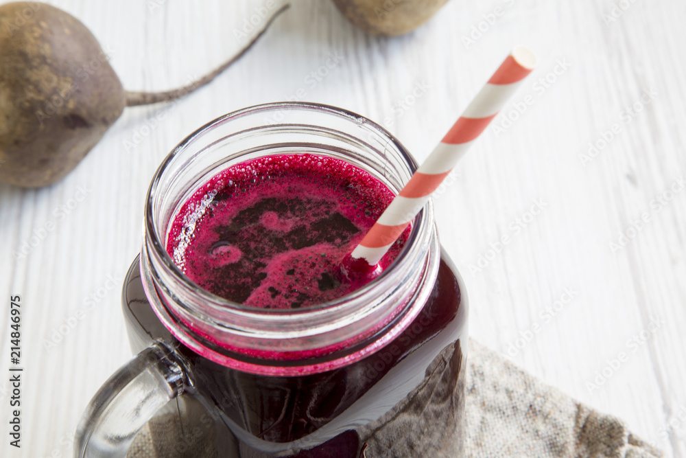 Glass jar mug filled with beetroot smoothie, low angle.