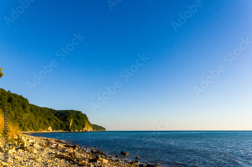 rocky sea shore with pebble beach, waves with foam