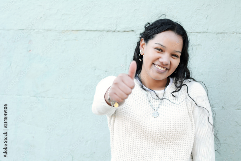 Portrait of beautiful latin teen girl doing thumbs up symbol
