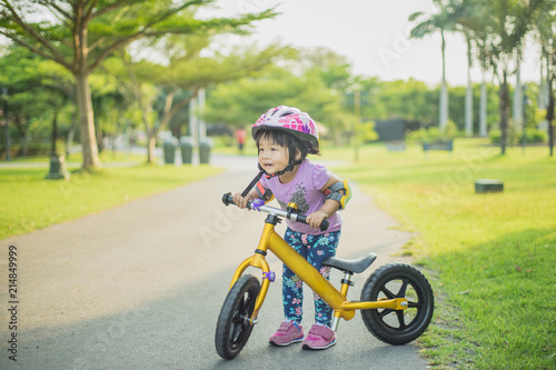 Little asian girl learning to ride balance bike in the park