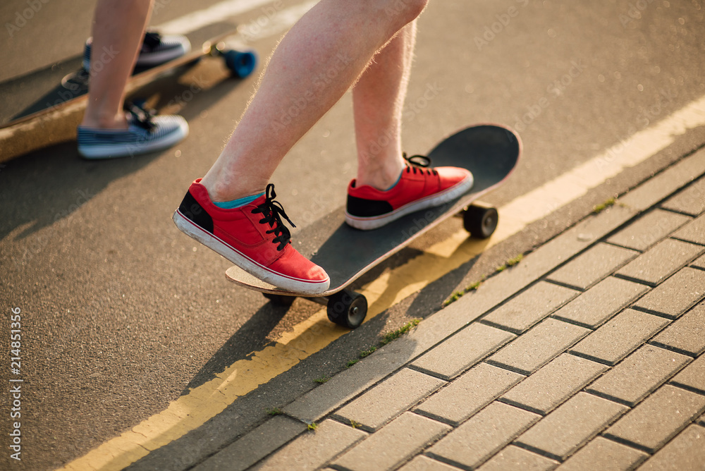 Happy young couple having fun with skateboard on the road. Young man and woman skating together on a sunny day. Happy young couple having fun with skateboard on the road. Young man and woman skating together on a sunny day.