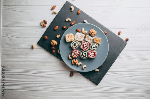 Foto Traditional oriental sweets and nuts: hazelnuts, cashews on a white wooden background
