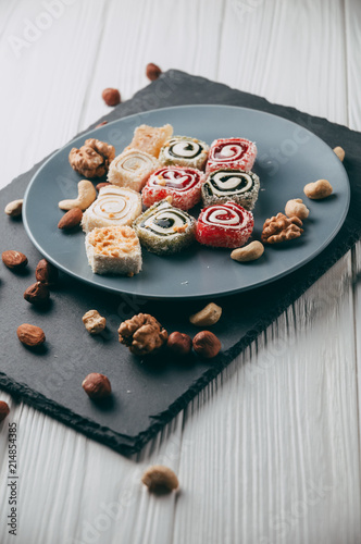 Foto Traditional oriental sweets and nuts: hazelnuts, cashews on a white wooden background