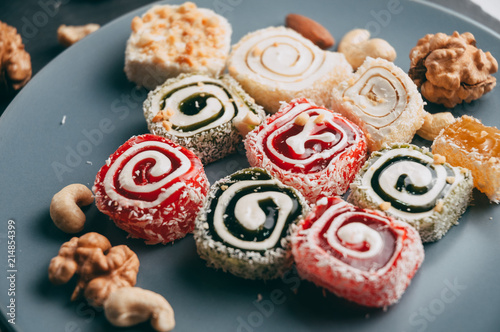 Traditional oriental sweets and nuts: hazelnuts, cashews on a white wooden background. Turkish dessert is the locus of Rahat. View from above. Place under the text. photo