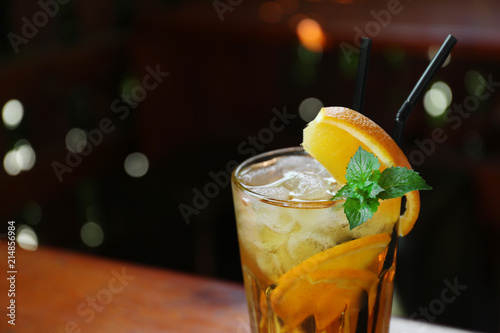 Glass of delicious cocktail with ice on blurred background, closeup