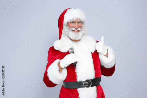 Santa Claus singing into microphone on color background. Christmas music