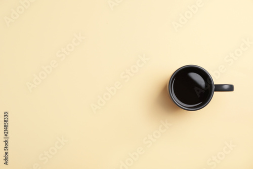 Ceramic cup with hot aromatic coffee on color background, top view