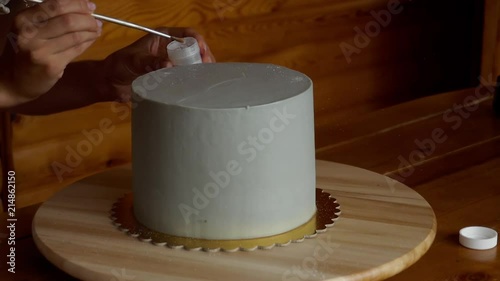 A close-up of an unrecognizable confectioner is adorned with a gray cake of silver chandurin photo