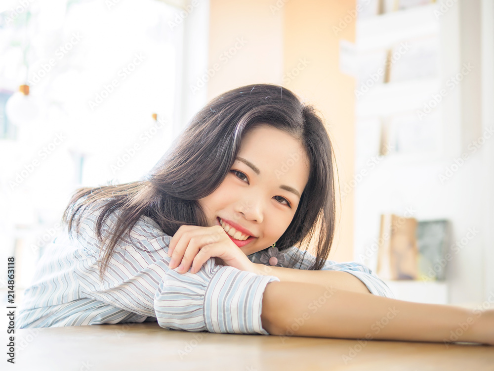 Young Chinese girl sitting in cafe, lying and looking at camera with smile face. Young Chinese girl sitting in cafe, lying and looking at camera with smile face.