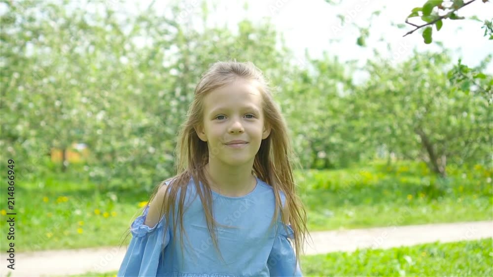 Adorable little girl in blooming apple garden on beautiful spring day Adorable little girl in blooming apple garden on beautiful spring day