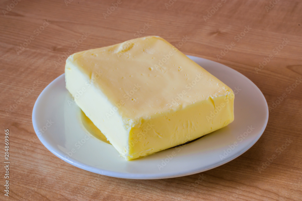 Butter on a white plate on a wooden table.